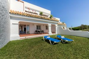 a yard with two blue chairs and a house at Villas Flamenco Beach Conil in Conil de la Frontera