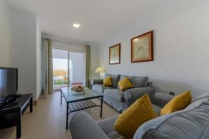 a living room with a couch and a tv at Villas Flamenco Beach Conil in Conil de la Frontera