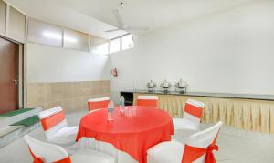 a dining room with a red table and white chairs at Treebo Trend Iffco Chowk in Gurgaon