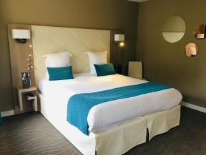 a bedroom with a large white bed with two blue pillows at Hôtel Le Normandy - Maison Tassoni in Vernon
