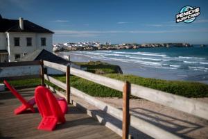 two red chairs sitting on a boardwalk next to the beach at Estúdios Lagido - Peniche Surf Camp Working Space & surf in Ferrel