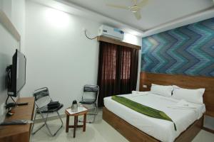 a bedroom with a bed and a tv and chairs at Hotel BG Inn in Bangalore