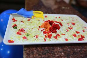 eine weiße Platte mit Kohl und Rosen auf dem Tisch in der Unterkunft Hotel BG Inn in Bangalore