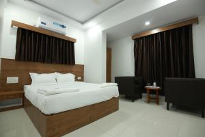 a bedroom with a bed and a desk and a television at Hotel BG Inn in Bangalore