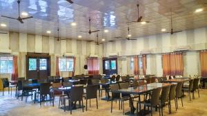 a dining room with tables and chairs and windows at Bodh Valley Resort in Igatpuri