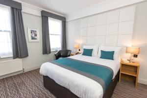 um quarto de hotel com uma cama grande com almofadas azuis em Kingscliff Hotel em Clacton-on-Sea