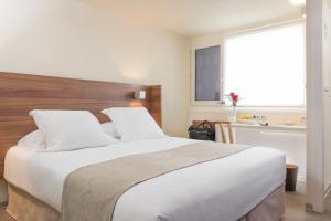 a bedroom with a large white bed and a window at Terre de Provence Hôtel & Spa in Le Pontet
