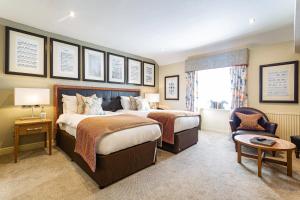 a hotel room with two beds and a chair at The Castle Hotel, Conwy, North Wales - The Coaching Inn Group in Conwy