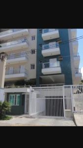 a white fence in front of a tall building at Condomínio Canto Verde in Ubatuba