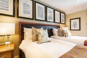 two beds in a bedroom with pictures on the wall at The Castle Hotel, Conwy, North Wales - The Coaching Inn Group in Conwy