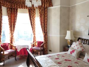 a bedroom with a bed, chair, and window at The Montclare & Cumberland in Llandudno