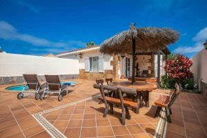 a patio with a table and chairs and an umbrella at La Maison de la Plage, by Comfortable Luxury in Corralejo