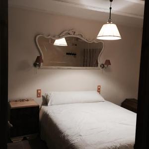 1 dormitorio con cama blanca y espejo en La casita de la dormilona, en Algimia de Almonacid