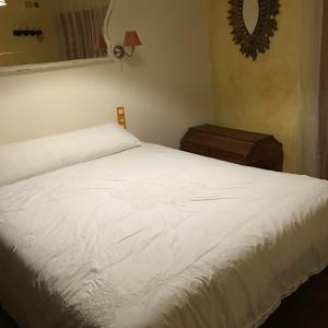 1 dormitorio con cama blanca y espejo en La casita de la dormilona, en Algimia de Almonacid