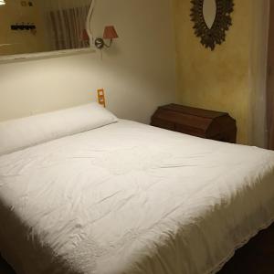 a bedroom with a white bed and a mirror at La casita de la dormilona in Algimia de Almonacid