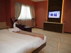 a hotel room with a bed and a flat screen tv at Sonia Hotel in Ouagadougou