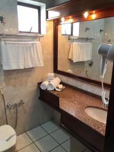 a bathroom with a sink and a mirror and a toilet at Hotel Residencial Itapema in Itapema