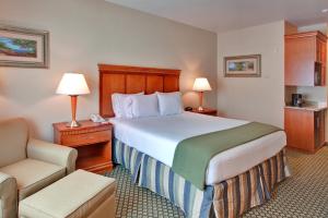 Cette chambre comprend un grand lit et une chaise. dans l'établissement Holiday Inn Express Hotel & Suites Ontario Airport-Mills Mall, an IHG Hotel, à Rancho Cucamonga