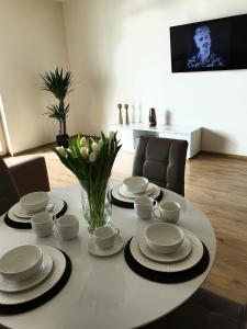 a table with plates and cups and a vase with flowers at Sea View Apartment in Klaipėda in Klaipėda