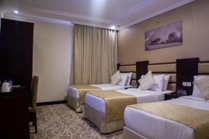a hotel room with two beds and a table at Al JAWHRA TOWER HOTEL in Mecca +52 photos