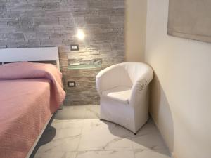 a bedroom with a white chair next to a bed at Carmine's holiday home in Torre Annunziata