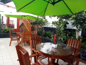 een patio met tafels en stoelen met groene parasols bij Hospedaje Fremiott in Huanchaco
