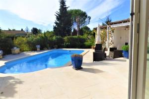 a swimming pool in a yard with a patio at Ibis - villa avec piscine, jardin et parking in Arles