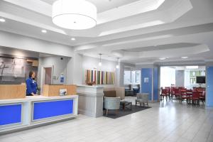 Holiday Inn Express & Suites - Valdosta, an IHG Hotel في فلدوستا: امرأة تقف عند كونتر في ردهة المستشفى