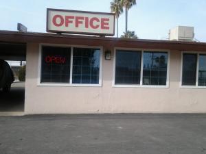 a store with an open sign in the window at Budget Inn in Tulare