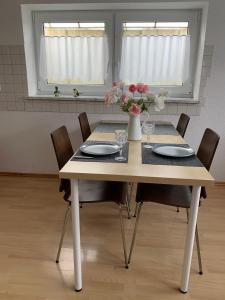 een eettafel met stoelen en een vaas met bloemen bij Ferienwohnung Stella in Ichenhausen