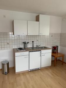 - une cuisine avec des placards blancs et un évier dans l'établissement Ferienwohnung Stella, à Ichenhausen