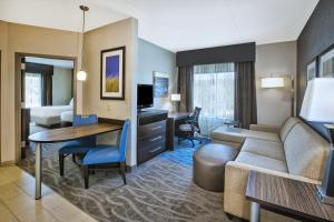 Holiday Inn Express & Suites Dayton South - I-675 by IHG في Shanersville: غرفة معيشة مع أريكة ومكتب في غرفة فندق