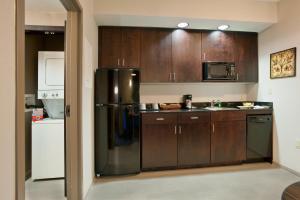 Holiday Inn Express & Suites Dayton South - I-675 by IHG في Shanersville: مطبخ مع خزائن خشبية وثلاجة من الفولاذ المقاوم للصدأ