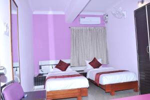 - une chambre avec 2 lits et une fenêtre aux murs violets dans l'établissement Brahma Inn, à Bangalore