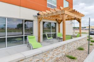 eine Terrasse mit grünen Stühlen und einer hölzernen Pergola in der Unterkunft Holiday Inn Express & Suites - Ogallala, an IHG Hotel in Ogallala