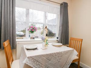 a dining room table with two chairs and a window at The Barn in Dimlington