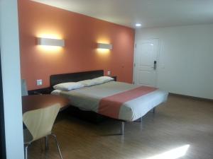 a bedroom with a large bed with orange walls at Motel 6 Bell Gardens in Bell Gardens