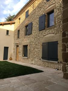 um edifício de tijolos com portas pretas em La Maison de Paul & Margaux em Châteauneuf-de-Galaure