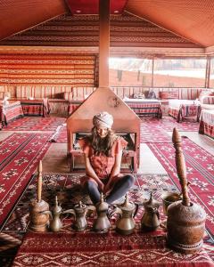 a woman sitting in a chair in a room with tea pots at golden day in Wadi Rum
