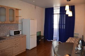 uma cozinha com um frigorífico e uma mesa com um micro-ondas em Apartment Belinskogo 86 em Yekaterinburg