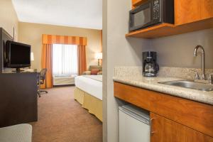 a hotel room with a kitchen with a sink and a bed at Holiday Inn Express & Suites - Muncie, an IHG Hotel in Muncie