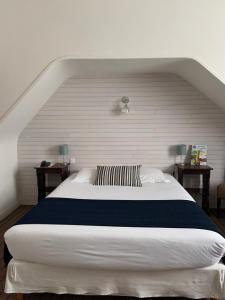 Cette chambre comprend un grand lit blanc et deux tables. dans l'établissement Hôtel De France - Restaurant L'insolite, à Douarnenez
