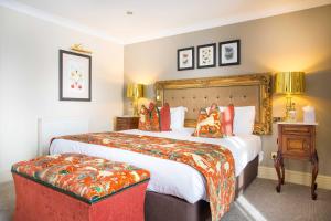 a hotel room with a large bed with orange pillows at The Castle Hotel, Conwy, North Wales - The Coaching Inn Group in Conwy