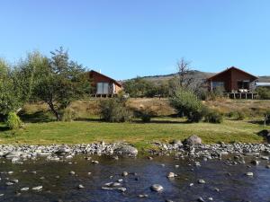 a view of a river with a house in the background at Cabañas Tela in Lonquimay