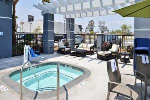 eine Terrasse mit einem Pool, Stühlen und einem Sonnenschirm in der Unterkunft Holiday Inn Express Hotels & Suites Loma Linda, an IHG Hotel in Loma Linda