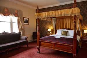 a bedroom with a canopy bed and a chair at Lamb Hotel by Greene King Inns in Ely
