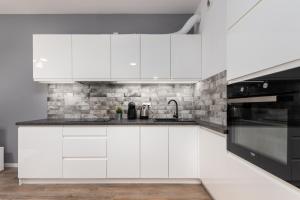 a kitchen with white cabinets and black appliances at Rakowska 14A 1 bedroom by Homeprime in Warsaw