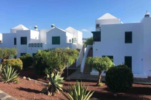 un edificio blanco con árboles delante de él en Paradiso Canario Playa Blanca, en Playa Blanca