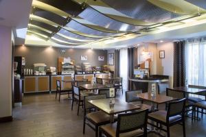 Holiday Inn Express & Suites - Oxford, an IHG Hotel في أكسفورد: مطعم بطاولات وكراسي وكاونتر