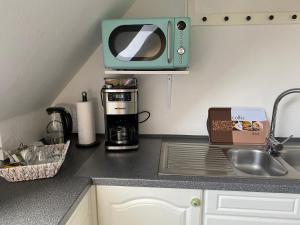 encimera de cocina con cafetera y microondas en De lütte Moehl, en Hollingstedt